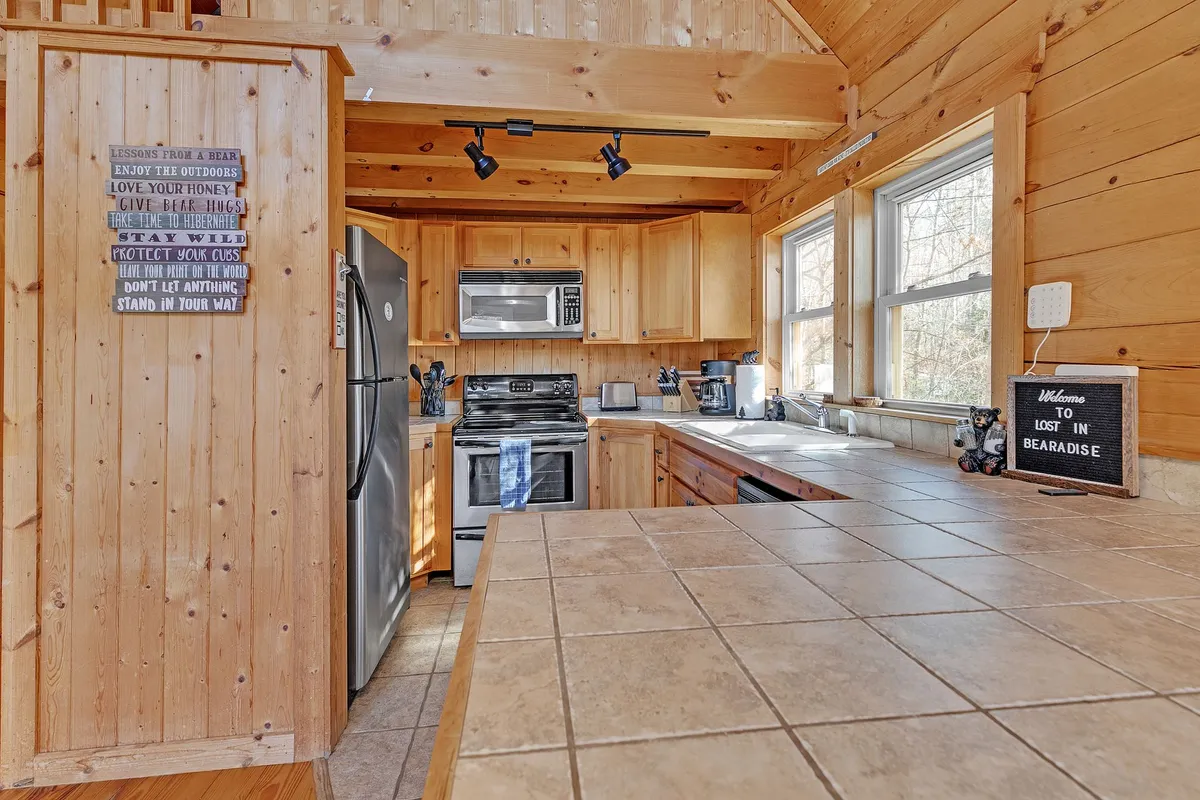 A kitchen-focused scene showcasing a central kitchen island, stainless steel appliances, rich wooden cabinetry, and thoughtfully arranged countertop decor. The open, inviting atmosphere is ideal for socializing, cooking together, and enjoying shared traditions.